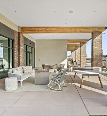 A modern outdoor patio with a white sofa, chairs, and a coffee table.